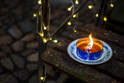 Close-up of illuminated tea light on retaining wall