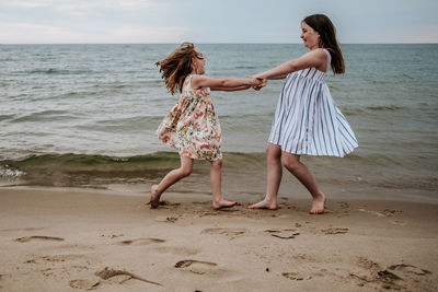 Girls spinning and playing on beach along lake michigan