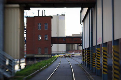 Road with tracks amidst buildings against sky