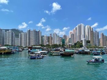 Boats moored in sea against buildings in city