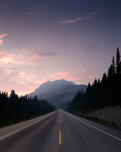 Road by mountains against sky during sunset