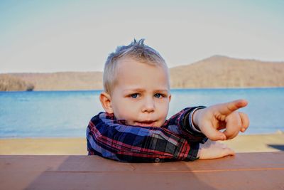 Portrait of cute boy pointing while leaning on table