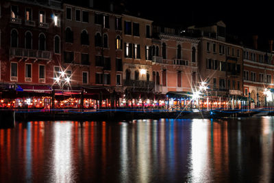 Illuminated buildings by river at night