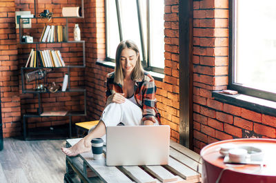 Woman sitting in a stylish loft working on a laptop.