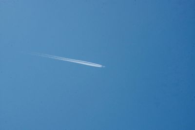 Low angle view of airplane flying against clear blue sky