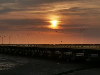 Bridge over street against orange sky