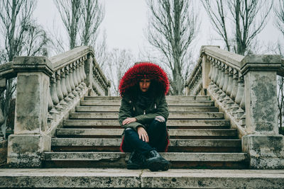 Full length portrait of woman sitting on staircase