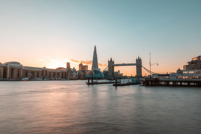 View of bridge over river by buildings against sky