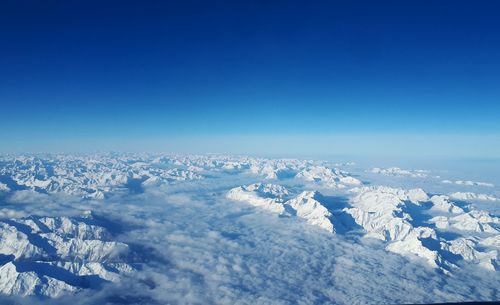 Aerial view of snowcapped mountains against clear blue sky