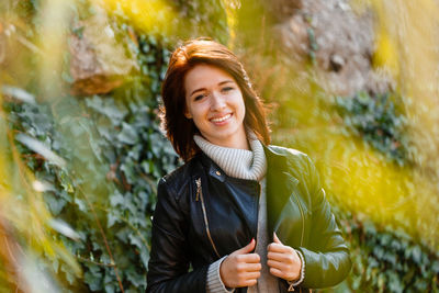 Beautiful young woman with light brown hair in a gray sweater and black leather