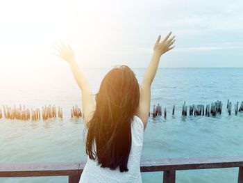 Rear view of woman standing in sea against sky