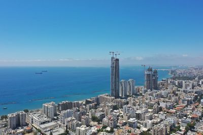 Aerial view of buildings and sea against blue sky