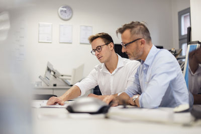 Two businessmen discussing plan on desk in office