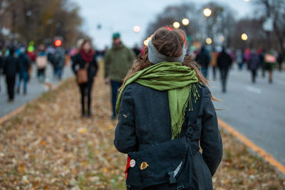 Rear view of woman with umbrella standing on street during winter