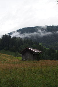 Barn on grassy field against mountain