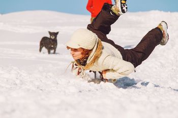 Young woman sledding on snow covered field during winter