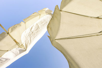 Low angle view of flags against clear blue sky