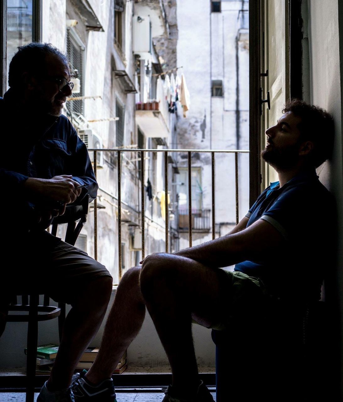 SIDE VIEW OF YOUNG MAN SITTING AT WINDOW