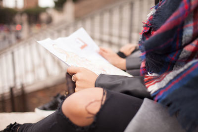 Midsection of woman holding paper outdoors