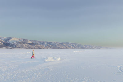 Walking on frozen lake with snowcapped mountains as background