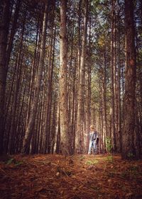 Rear view of man standing by trees in forest