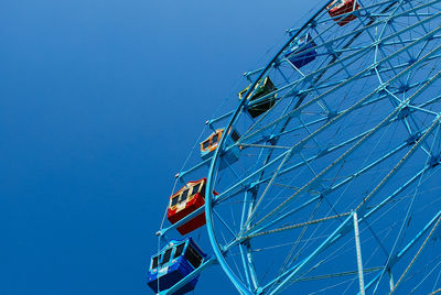 Low angle view of ferris wheel against blue sky