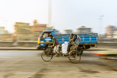 Rear view of man riding cycle rickshaw on street