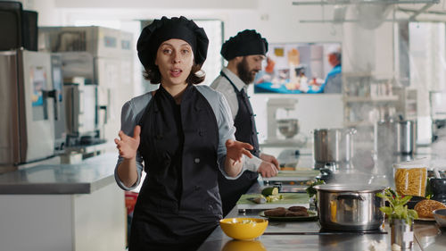 Portrait of chef gesturing while standing by kitchen counter