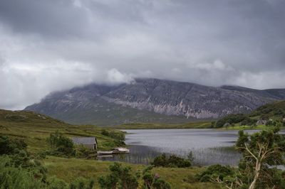 Scenic view of mountains and lake against cloudy sky