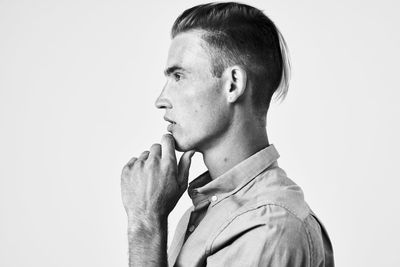 Portrait of young man looking away against white background
