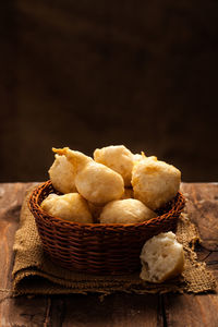 Close-up of bread in basket on table against black background