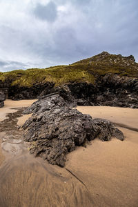 Rock formations on beach against sky