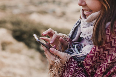 Midsection of woman using mobile phone on land