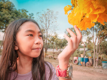 Girl looking at orange flower in city