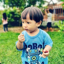 Portrait of cute boy holding camera on field