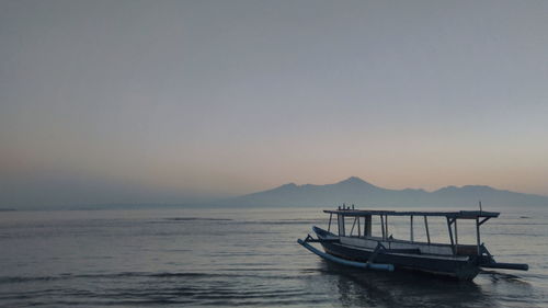 Fishing boat in sea against sky during sunset