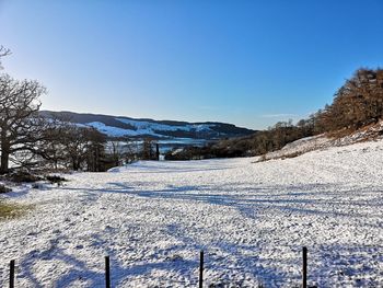 Snow covered field against clear sky