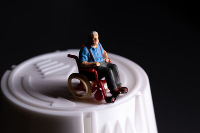 Elderly senior citizen sitting in a wheelchair that is on a medicine bottle healthcare concept