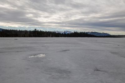 Scenic view of frozen landscape against sky during winter