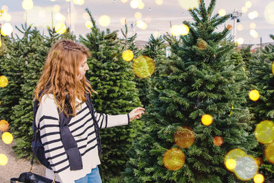 Rear view of woman holding christmas tree