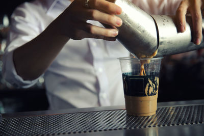 Close-up of hand pouring coffee in glass