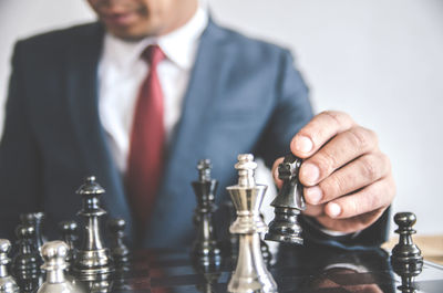 Midsection of businessman playing chess against white background