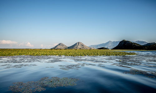 Scenic view of lake by mountains against sky