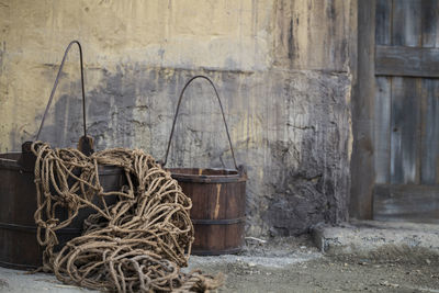 Old wooden buckets and rope on floor against old weathered wall in building