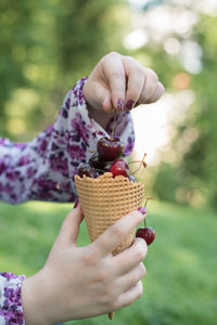 Close-up of woman holding cherries in waffle cone