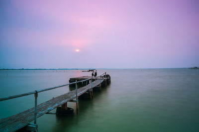 Pier over sea against sky during sunset