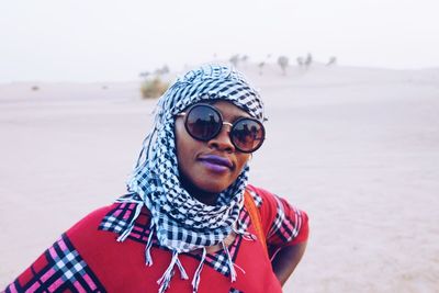 Portrait of smiling woman wearing kaffiyeh and sunglasses at desert on sunny day