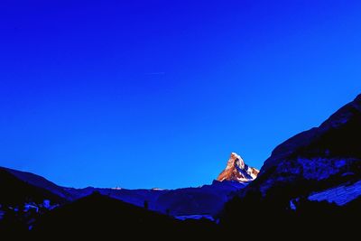 Dog on snowcapped mountains against clear blue sky