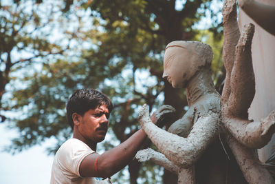 Low angle view of man statue against trees