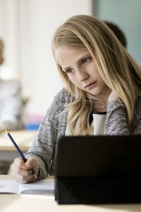 Thoughtful girl sitting at desk in classroom